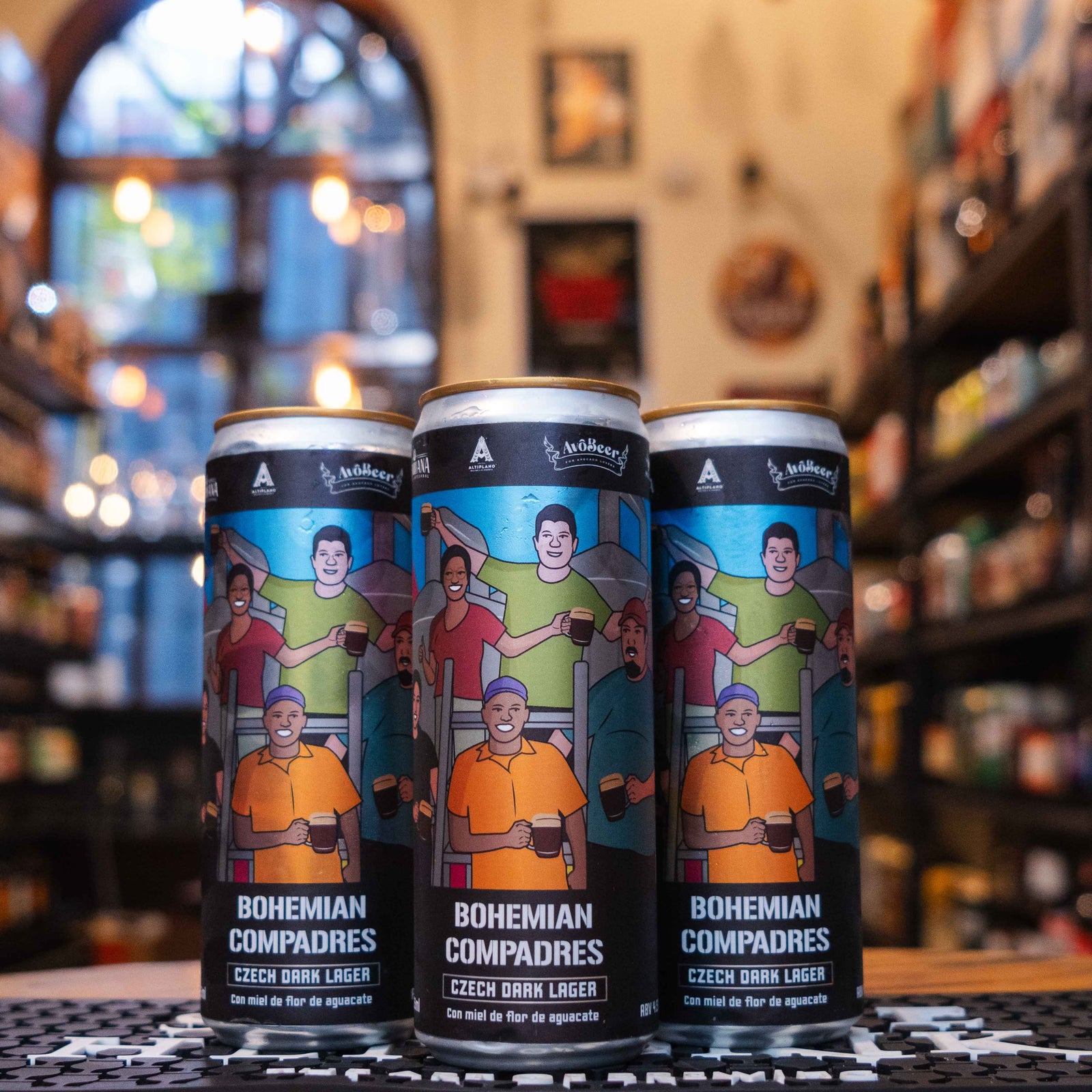 AvoBeer Bohemian Compadres, una Czech Dark Lager mexicana de AvoBeer. La etiqueta destaca tonos oscuros y un diseño moderno. Con 5% ABV, ofrece un sabor equilibrado de malta, suave amargor y un toque único de aguacate. Ideal para acompañar tacos, quesos suaves y ensaladas frescas. Refleja el carácter artesanal y distintivo de esta cerveza.