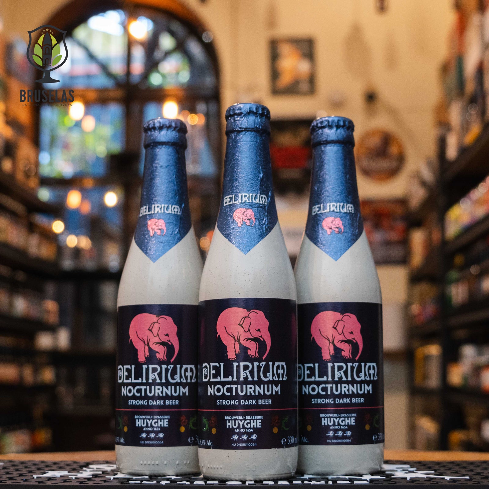 Botella de Delirium Nocturnum, una Belgian Dark Strong Ale de Brouwerij Huyghe. Con un ABV de 8.5%, esta cerveza oscura destaca por sus complejos aromas de caramelo, toffee, frutas oscuras como pasas y ciruelas, y especias como clavo y pimienta. En boca, ofrece sabores a malta tostada, chocolate, caramelo y un ligero amargor, con un final ligeramente seco. Ideal para maridar con carnes rojas, quesos maduros y postres de chocolate oscuro. Presentación en botella de 330 ml.