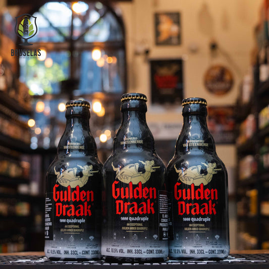 Botella de Gulden Draak 9000 Quadruple, una Quadrupel belga de Brouwerij Van Steenberge. La etiqueta negra presenta el emblemático dragón dorado. Con 10.7% ABV, ofrece notas de frutas secas y dulzor equilibrado. Ideal para acompañar carnes rojas, estofados y quesos fuertes.