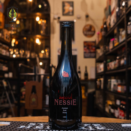 Botella de Imperial Nessie, una Ancient Red Stone Strong Ale con 8.7% ABV. Presenta notas de caramelo, frutas maduras y ligeros toques tostados, con un cuerpo sedoso y un final cálido. Ideal para maridar con carnes asadas, quesos añejos y postres de chocolate amargo. Su diseño elegante en botella de 750 ml refleja la exclusividad y robustez de esta cerveza artesanal.