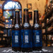 Botella de La Bru Maíz Azul, una Cream Ale de la cervecería mexicana La Bru, elaborada con maíz azul. La etiqueta es azul con detalles dorados y letras blancas en estilo moderno. Con un ABV de 4%, ofrece un sabor ligero, con notas dulces y terrosas del maíz. Ideal para acompañar tacos, tamales y enchiladas. Su diseño destaca la conexión con la gastronomía mexicana.