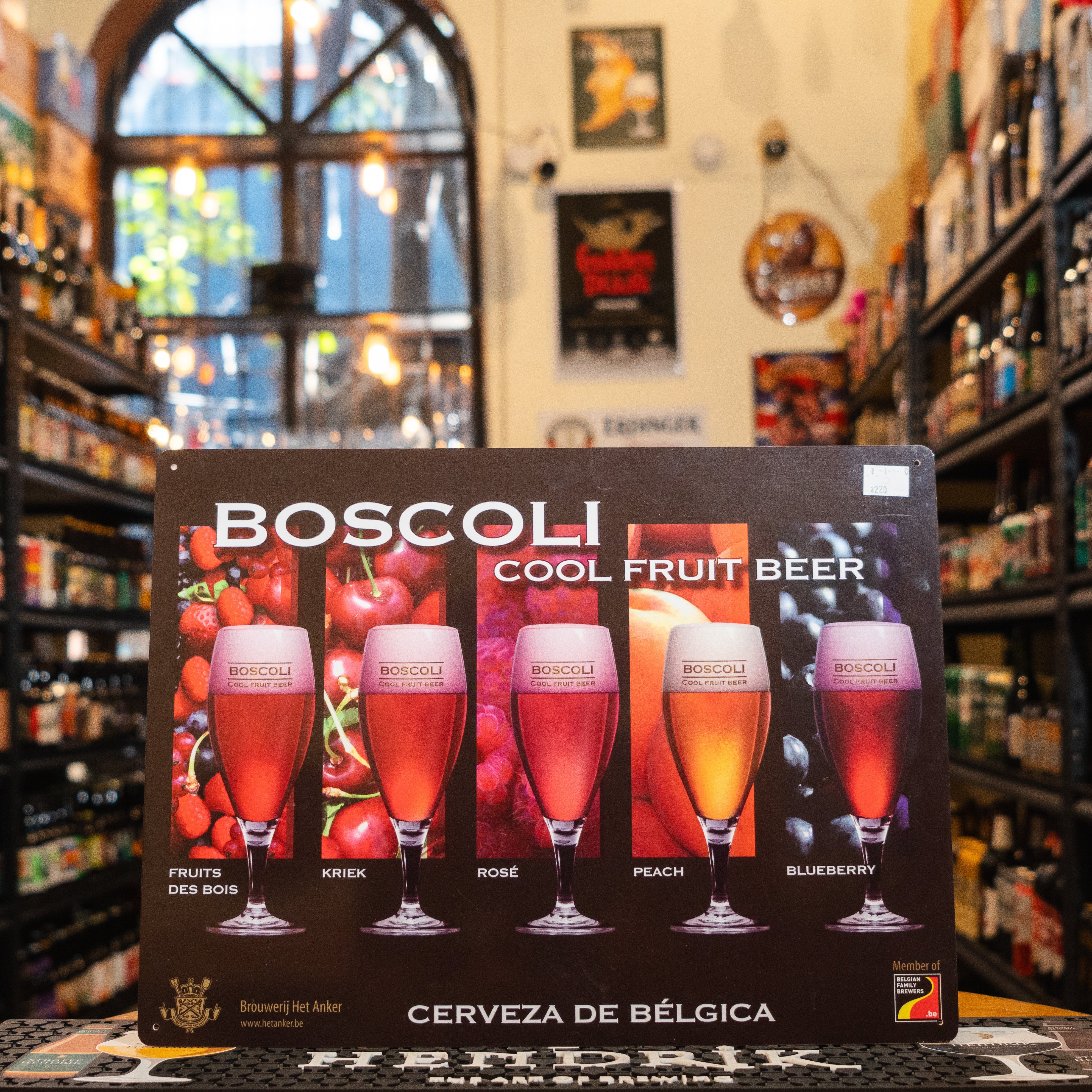 Letrero horizontal de Boscoli Cool Fruit Beer en una tienda especializada en cervezas. Su diseño muestra copas con cervezas afrutadas en tonos intensos, destacando las variedades y colores vibrantes.