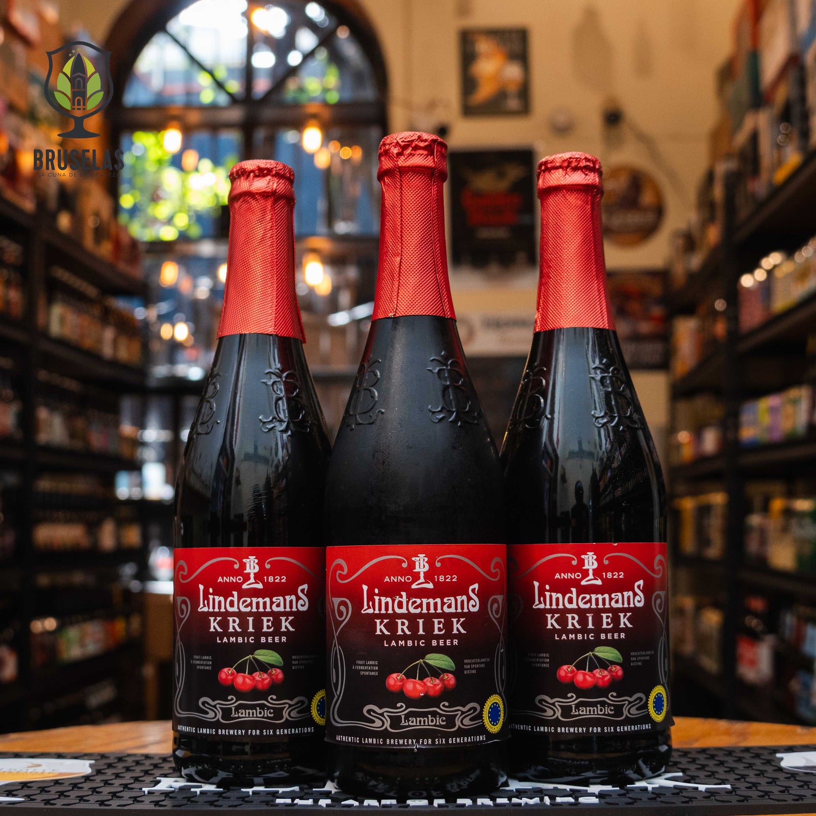 Botella de Lindemans Kriek, una cerveza estilo Fruit Lambic elaborada por Brouwerij Lindemans en Bélgica. La etiqueta roja y negra presenta cerezas en el centro y el logotipo de la cervecería. Con un ABV de 3.5%, ofrece un perfil de sabor dulce y ligeramente ácido, con notas a cereza y un toque de almendra. Ideal para acompañar postres frutales y quesos suaves. Presentación en botella de 750 ml.
