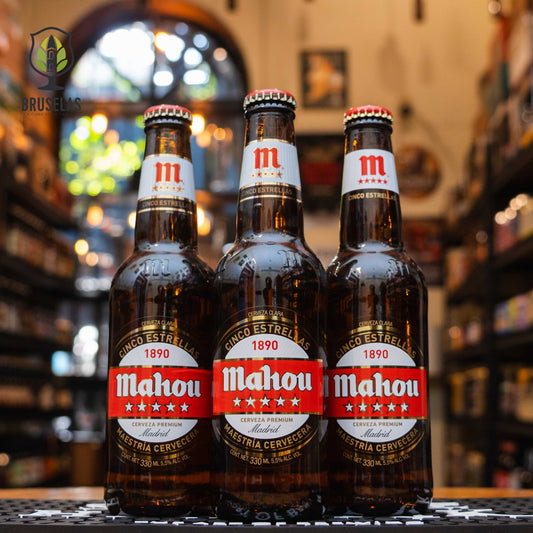 Botella de Mahou Cinco Estrellas, una lager premium de Grupo Mahou-San Miguel, elaborada en Madrid, España. La etiqueta es de color rojo y dorado, con el logotipo de la marca en blanco y la inscripción 'Cinco Estrellas 1890'. Con un ABV de 5.5%, ofrece un aroma fresco con notas herbales y un sabor balanceado entre cereal, hierbas y un toque cítrico. Ideal para acompañar tapas, pescados a la parrilla y quesos suaves.