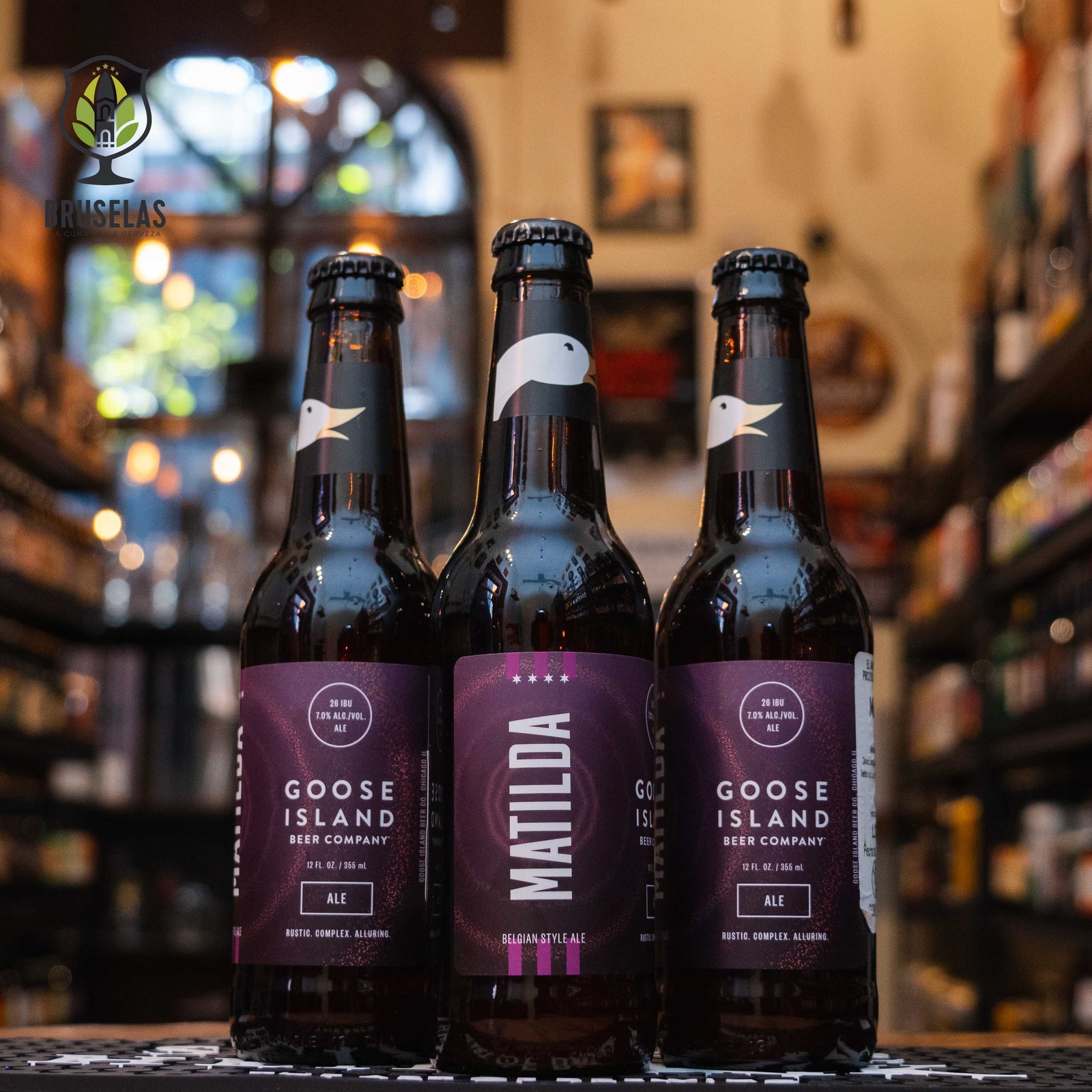 Botella de Matilda, una Belgian Strong Pale Ale de Goose Island Beer Co. La etiqueta presenta un diseño elegante en tonos cálidos, destacando el nombre de la cerveza en tipografía clara. Con un ABV de 7%, ofrece aromas florales y especiados, con notas de manzana, pera y levadura belga. Su sabor equilibra maltas dulces, caramelo y especias, con un final seco y ligeramente ácido. Ideal para maridar con quesos fuertes, carnes asadas y platos especiados.