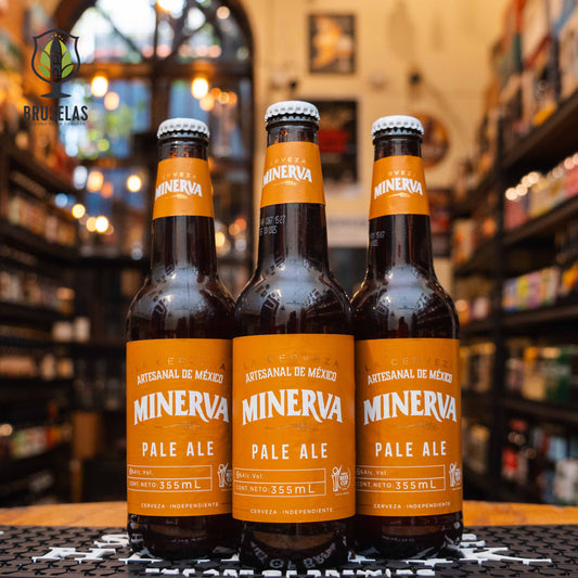 Botella de Minerva Pale Ale, una cerveza artesanal estilo English Pale Mild Ale de Cervecería Minerva, con 6% de alcohol, elaborada en Guadalajara, Jalisco. La etiqueta presenta un diseño en tonos ámbar, resaltando el carácter equilibrado de esta cerveza. Ofrece un perfil de sabor balanceado entre maltas caramelizadas y lúpulos cítricos, ideal para acompañar hamburguesas, pizzas, y quesos semicurados.