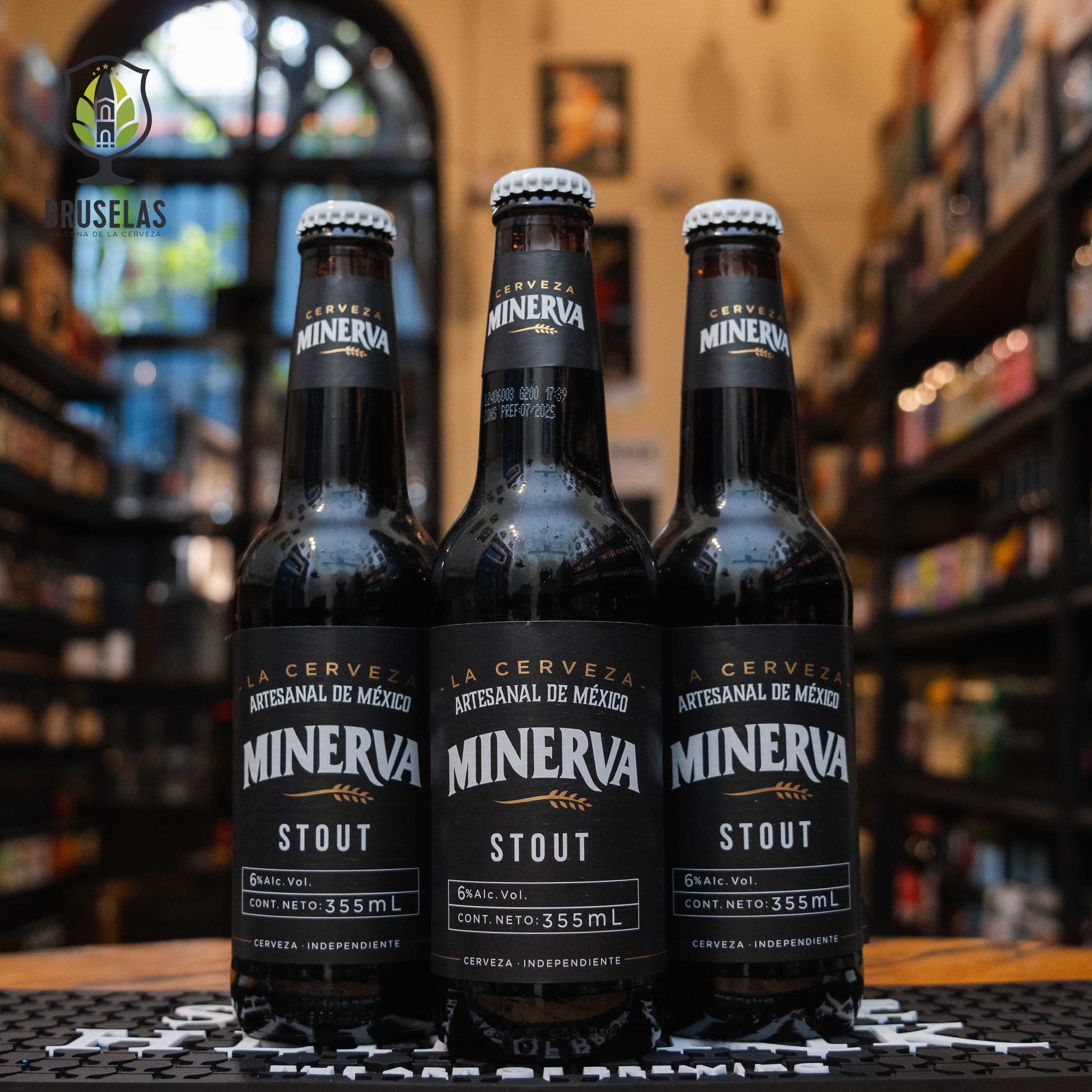 Botella de Minerva Stout, una cerveza artesanal estilo Irish Dry Stout de Cervecería Minerva en México. Con un ABV de 6%, esta cerveza destaca por su color negro profundo y un perfil de sabor robusto con notas de cacao, café y malta tostada. Ideal para maridar con cortes de carne, quesos fuertes y postres de chocolate como brownies. Su cuerpo cremoso y amargor suave la hacen una excelente opción para los amantes de cervezas intensas.