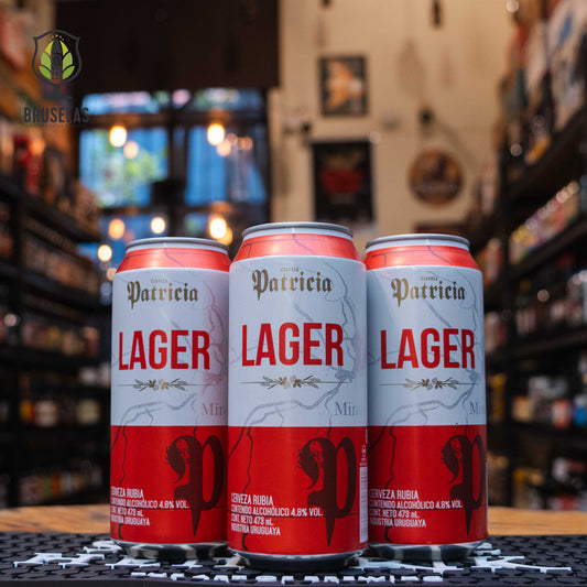 Patricia Lager, una cerveza tipo lager de Cervecería Patricia, elaborada en Uruguay. La etiqueta presenta un diseño de fondo blanco y rojo con el nombre 'Patricia' en letras doradas estilizadas y 'Lager' en letras rojas grandes. En la parte inferior, se detalla el contenido alcohólico de 4.8%. Ideal para acompañar carnes asadas, pizza y mariscos. El diseño de la botella refleja un estilo moderno y accesible.