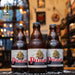 Botella de Piraat, una cerveza estilo Belgian Strong Pale Ale elaborada por Van Steenberge, Bélgica. La etiqueta muestra un barco pirata dorado sobre un fondo claro, con el nombre "Piraat" en letras rojas destacadas. Presenta un ABV de 10.5%, ofreciendo un perfil de sabor robusto, con notas de malta dulce, especias y un toque frutal. Ideal para acompañar carnes asadas y quesos fuertes.
