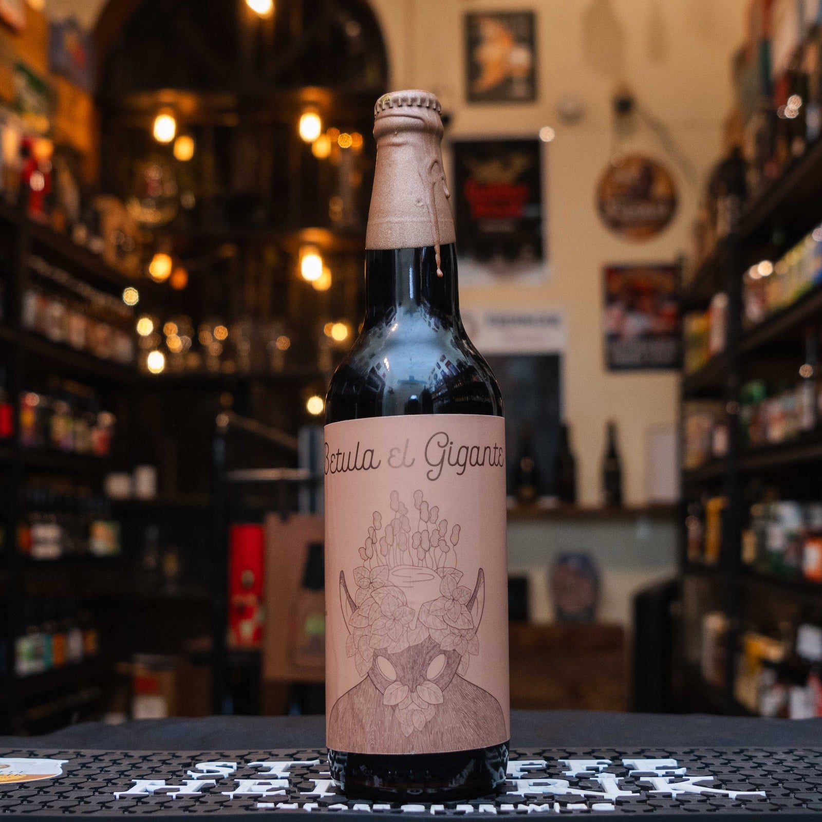 Botella de Rey Árbol Betula 2024 Crema de Maní, una Imperial Stout mexicana de Rey Árbol. La etiqueta beige muestra ilustraciones minimalistas con un diseño artístico único. Con un perfil cremoso y notas dulces de maní tostado y chocolate, ofrece un cuerpo pleno y un final equilibrado. Ideal para maridar con chocolates y postres con frutos secos. Su diseño refleja creatividad y sofisticación.