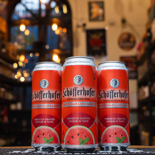 Lata de Schöfferhofer Watermelon Mint, una cerveza alemana estilo Radler con 2.5% ABV. Combina la suavidad de la Hefeweizen con notas dulces de sandía y frescura de menta. Su diseño destaca un fondo naranja vibrante con imágenes de sandía y menta. Ideal para días cálidos, marida bien con ensaladas, platos ligeros y postres frutales. Refrescante y ligera, perfecta para disfrutar al aire libre.