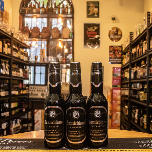 Botella de Samichlaus Schwarzes, una Doppelbock de Brauerei Schloss Eggenberg con un ABV del 14%, considerada una de las lagers más fuertes del mundo. De color oscuro y cuerpo denso, presenta aromas de malta tostada, chocolate negro y café. En boca, es rica y compleja, con sabores a caramelo y frutos secos, y un final cálido. Perfecta para acompañar postres de chocolate, quesos curados o disfrutarla como digestivo.