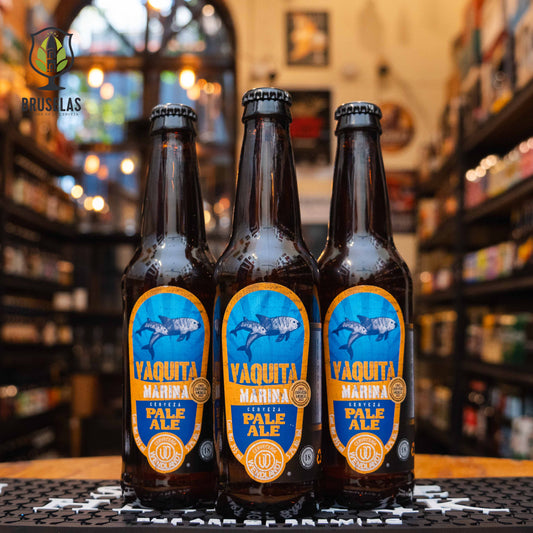 Botella de Vaquita Marina Pale Ale de Cervecería Wendlandt. La etiqueta es azul y naranja, con una ilustración de una vaquita marina. ABV de 5.2%. Sabor cítrico con un amargor moderado y un final refrescante. Ideal para acompañar carnes, pescados grasos y quesos añejos. El diseño refleja el compromiso de la cervecería con la vida marina y la conservación.