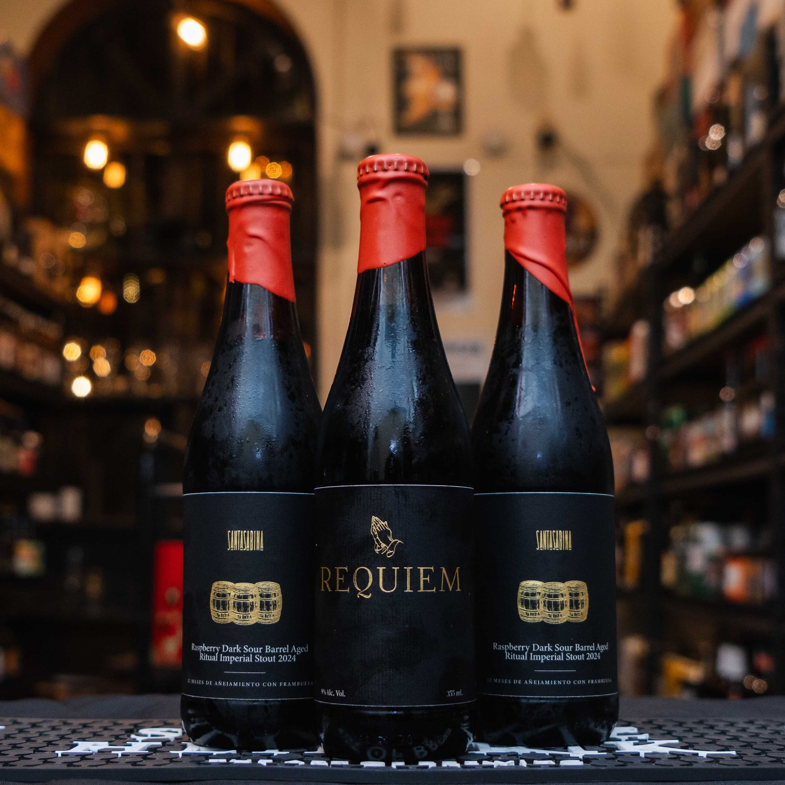 Botellas de Santa Sabina Requiem Dark Sour Barrel con frambuesa, envueltas en cera roja, exhibidas en tienda cervecera artesanal